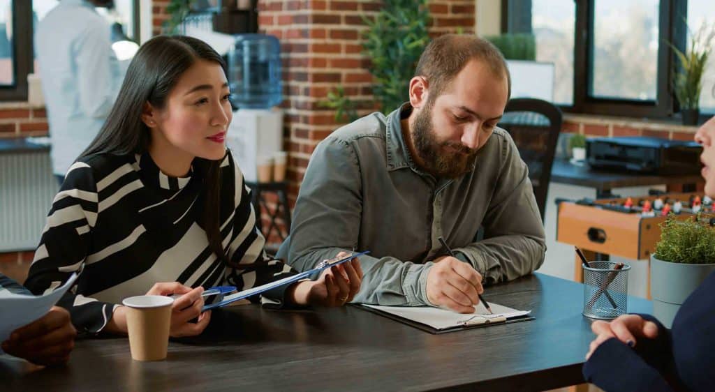 asian woman and a man at a table taking notes